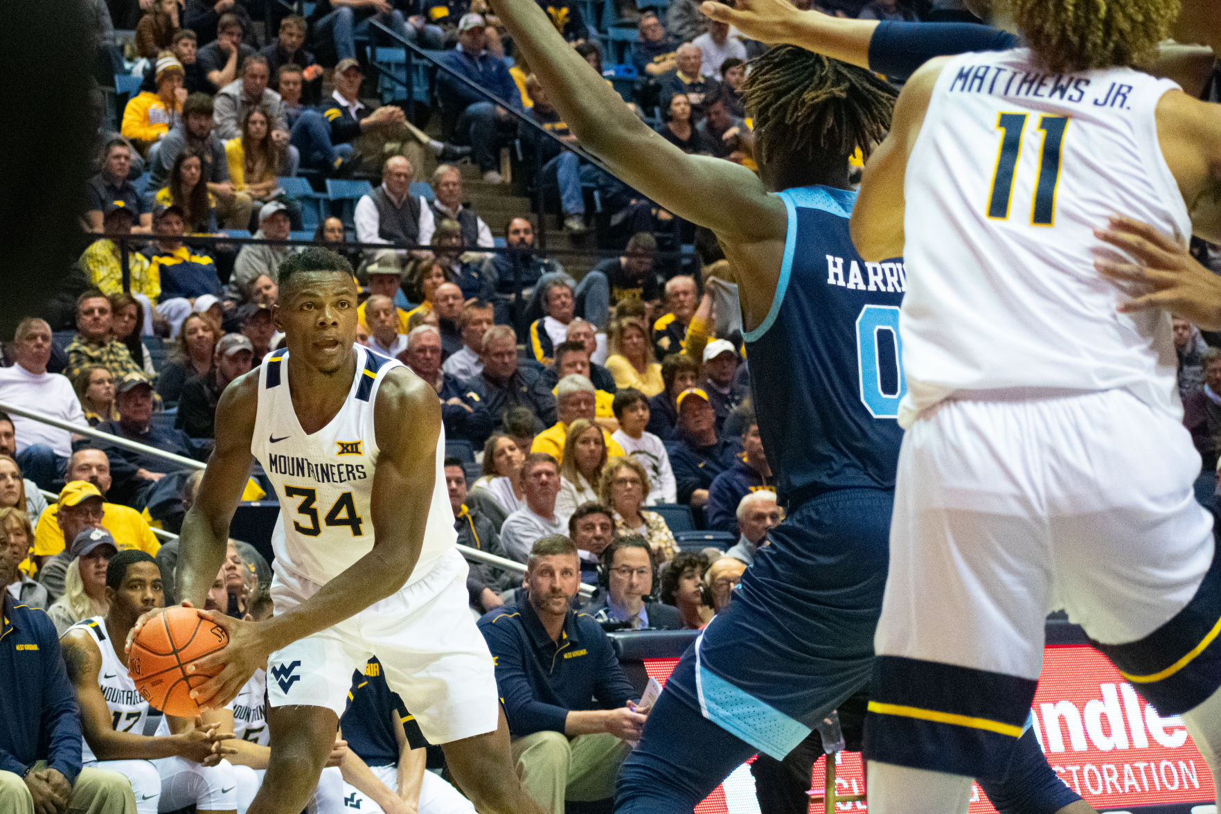 West Virginia forward Oscar Tshiebwe (34) looks to pass the ball to teammate Emmitt Mathews Jr. (11) against Rhode Island